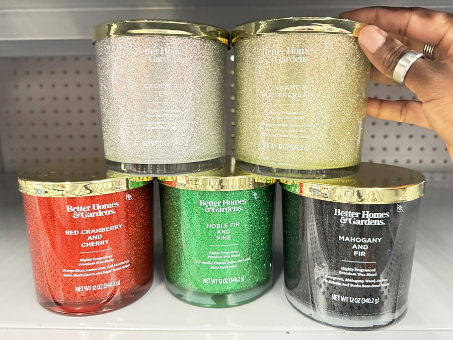 hand touching stack of glittery jar candles on store shelf