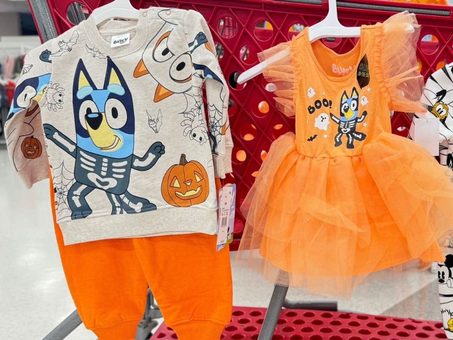 A Bluey Halloween Outfit and Dress hanging from a Target shopping cart