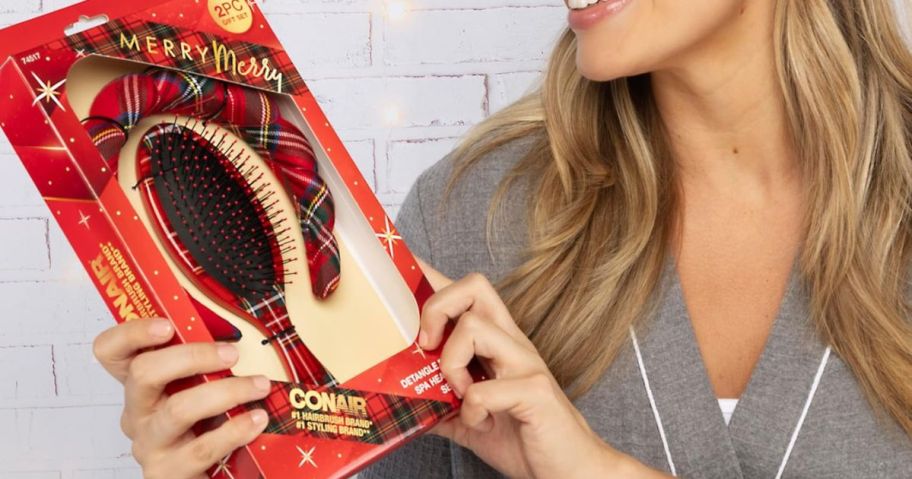 A woman holding a Conair Spa Tartan Headband & Detangle Cushion Brush