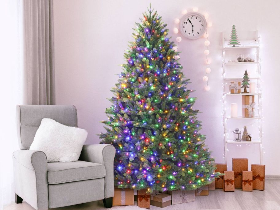 Holiday Living 7.5-ft Everett Fraser Fir Pre-lit LED Artificial Christmas Tree next to a chair and presents