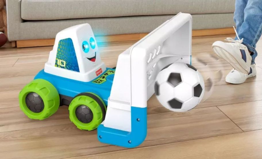 a kids foot kicking a soccer ball into a goaldozer toy