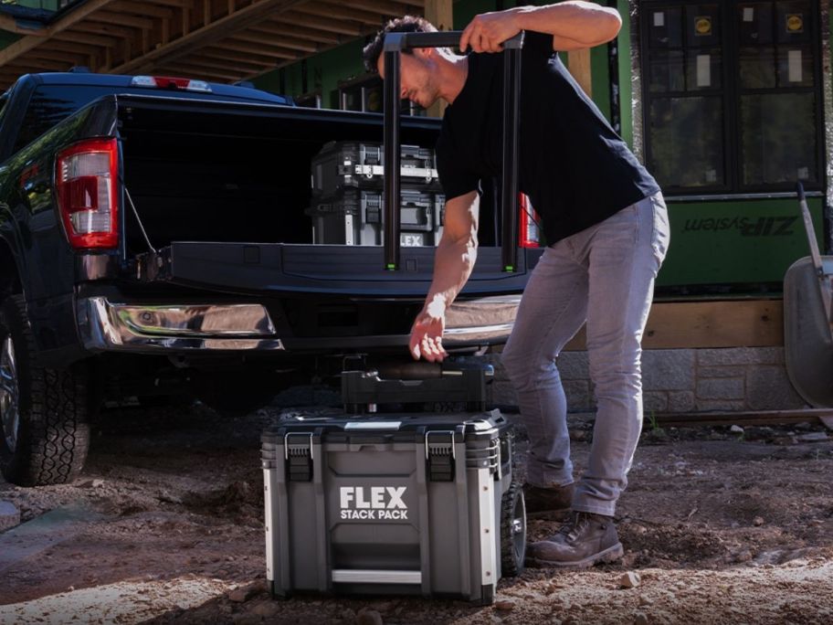 man taking the handle off the Flex Stack Pack 22-in W x 26.3-in H x 19.2-in D Gray Metal Rolling Tool Box before putting in the bed of a truck