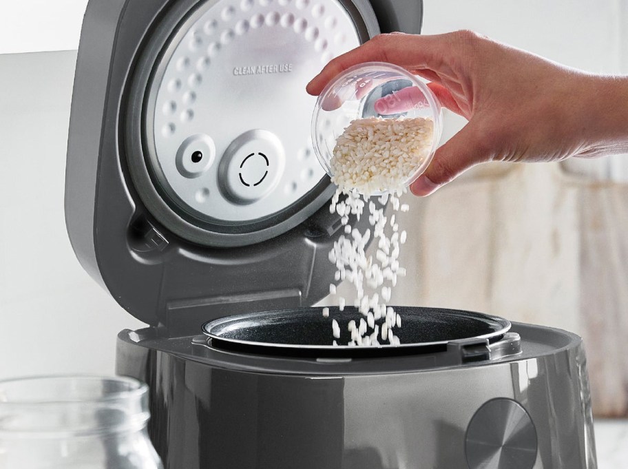 Green Pan rice cooker person pouring rice inside of it