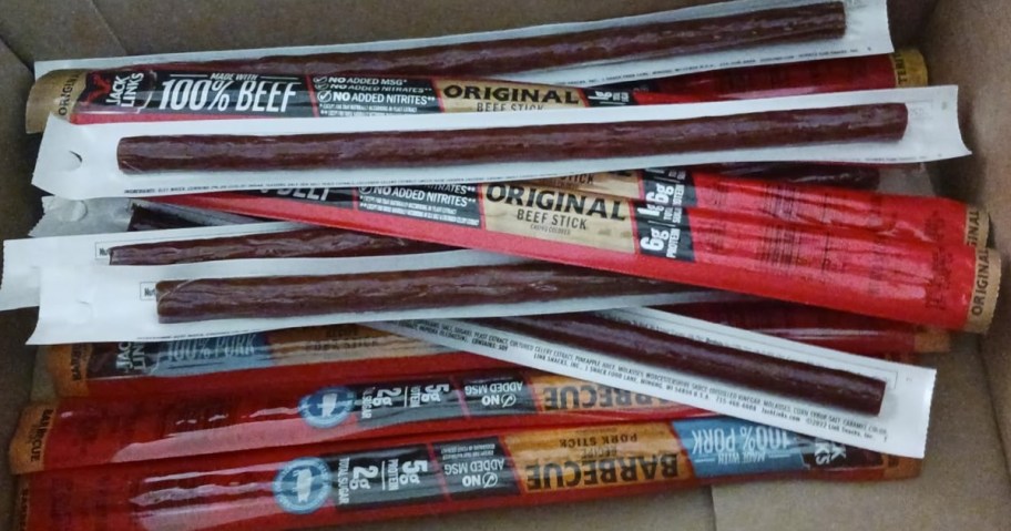 a variety of Jack Links Beef Sticks in various flavors in a cardboard box