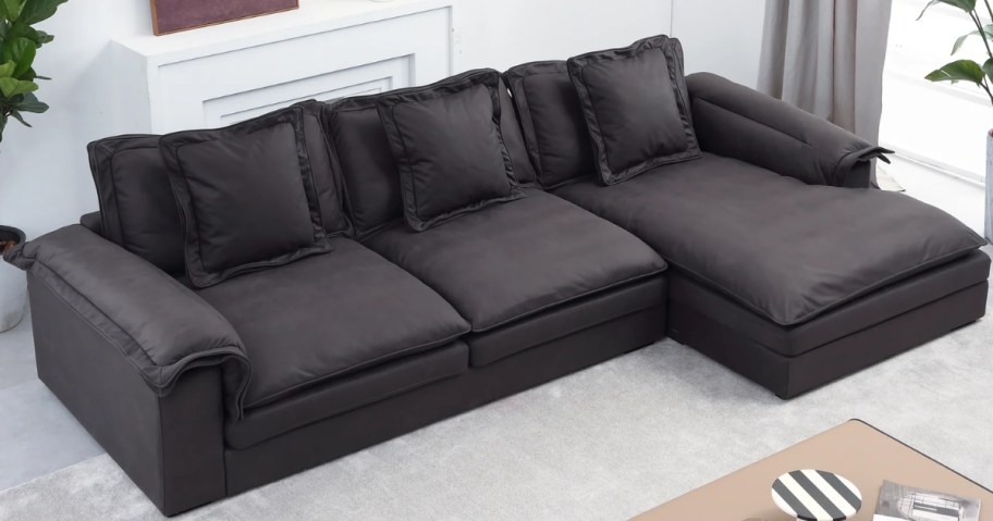 a large black couch with chaise lounge on one end in a living room