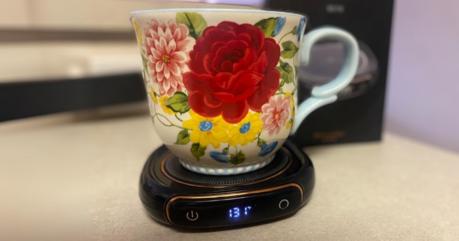 a floral coffee mug on a black electric coffee warmer on a kitchen counter