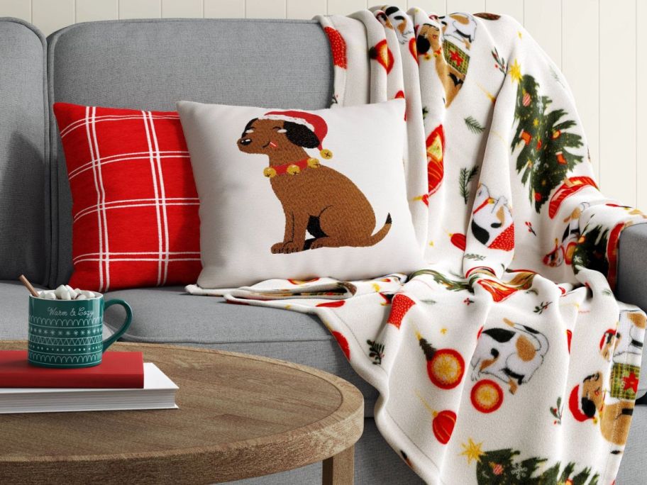 a puppy and kitty print blanket draped over a sofa and shown with throw pillows