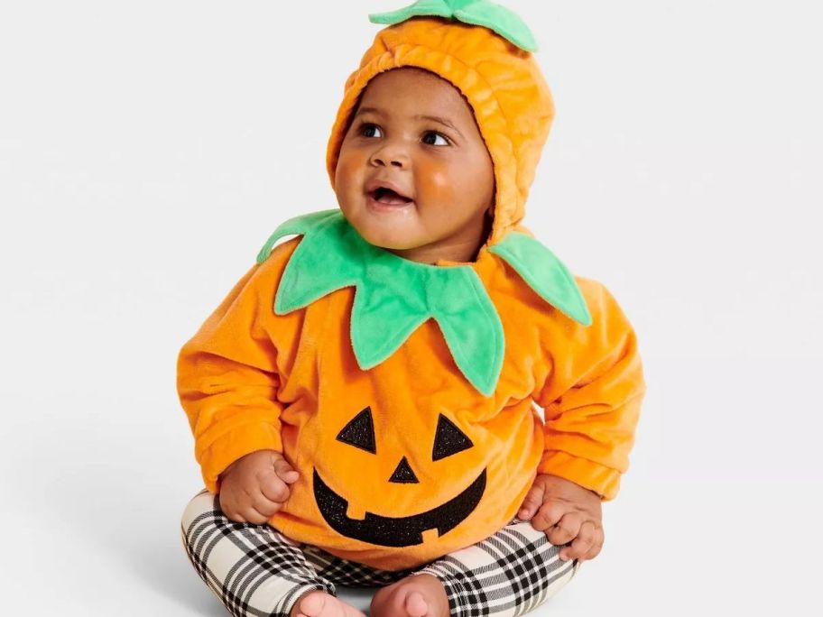 A toddler wearing a pumpkin costume