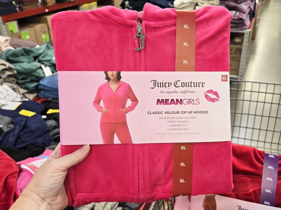 hand holding up a pink juicy jacket in store