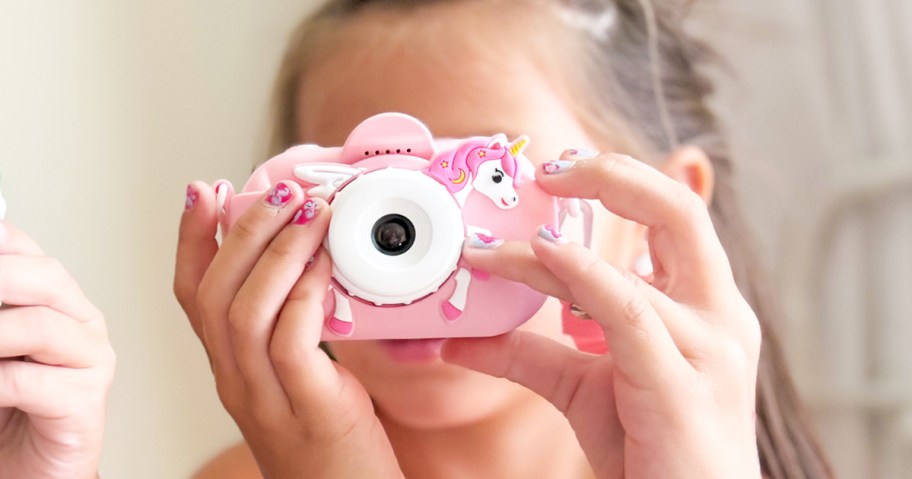 girl looking through a pink unicorn digital camera