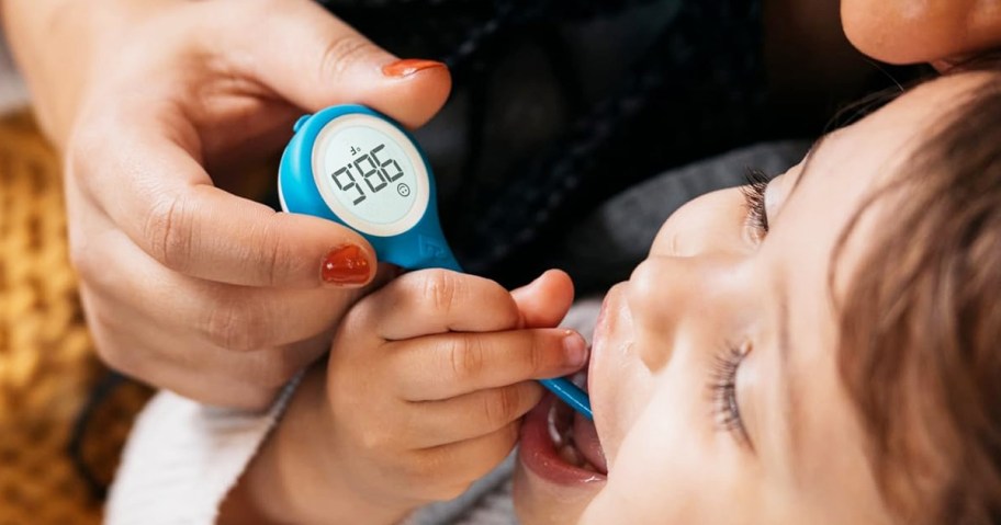 woman taking child's temperature with thermometer