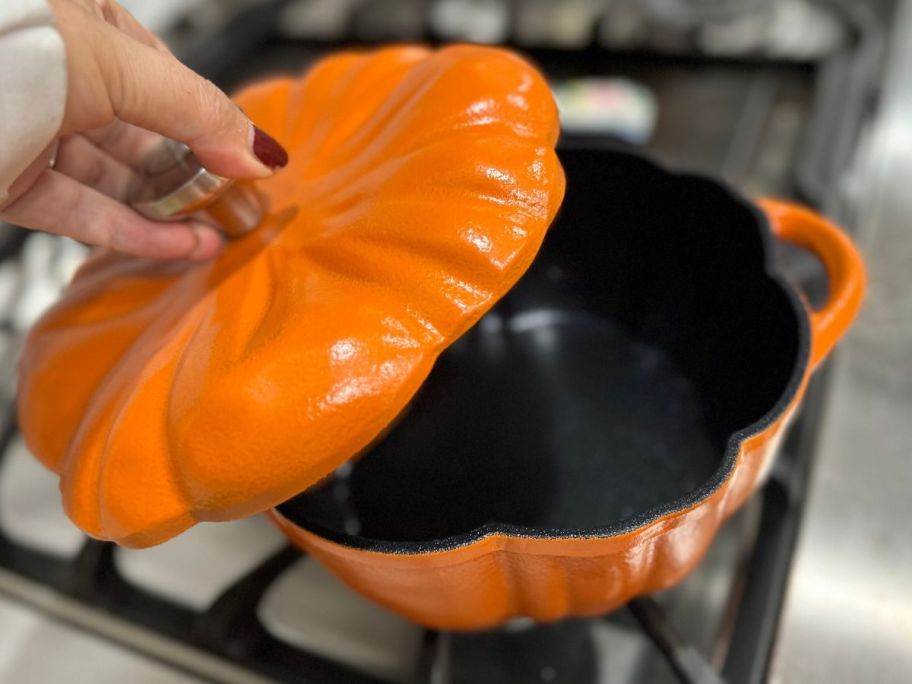 Hand taking the lid off of a Kitchen HQ Pumpkin Casserole 