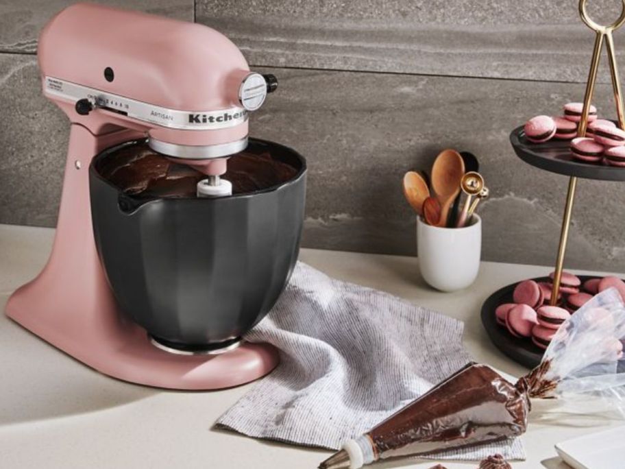 A pink KitchenAid Mixing Bowl with a black shell ceramic bowl next to a tiered tray of macarons