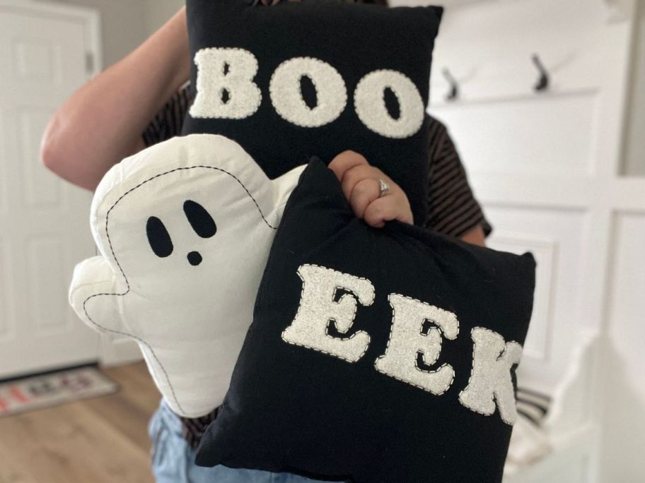 Woman holding 3 Halloween pillows from Kohl's