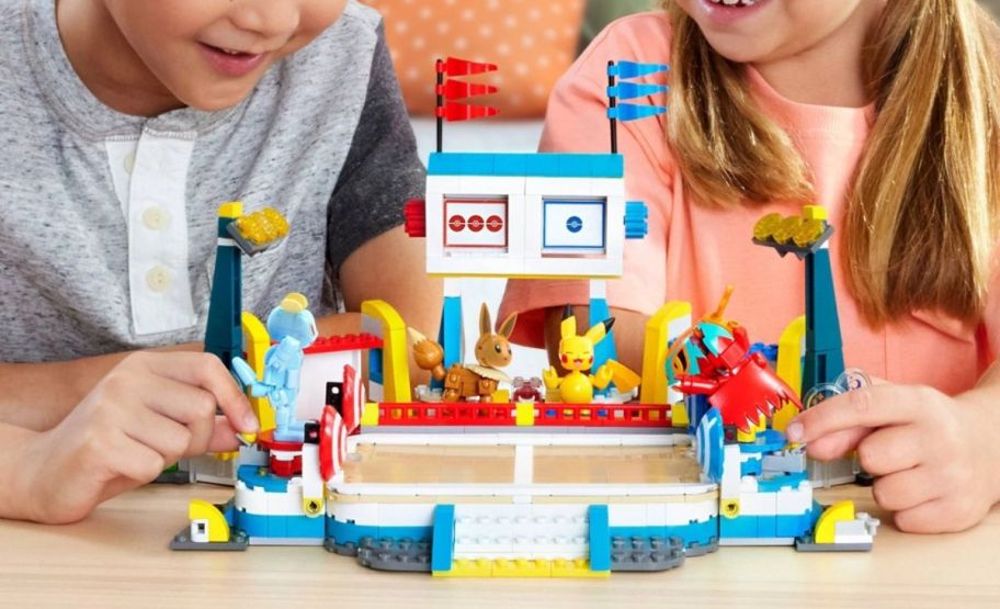 a boy and girl playing with a pokemon training stadium building kit