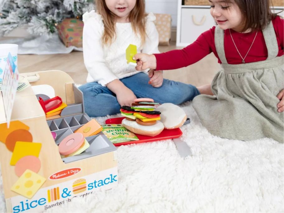 two little girls playing with a Melissa & Doug Wooden Slice & Stack Sandwich Counter Playset