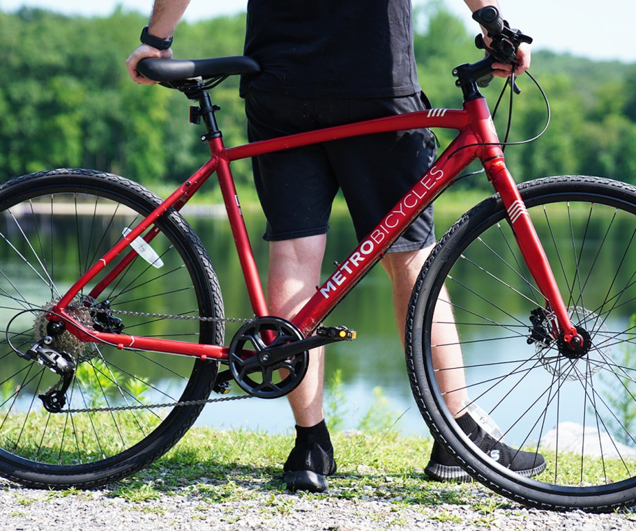 man standing behind a red bicycle