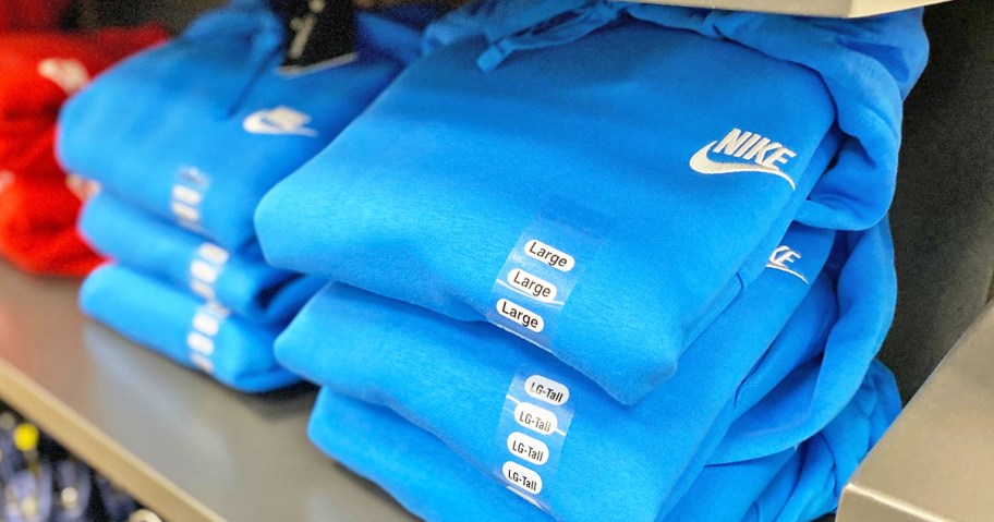 stacks of folded blue nike hoodies on store shelf