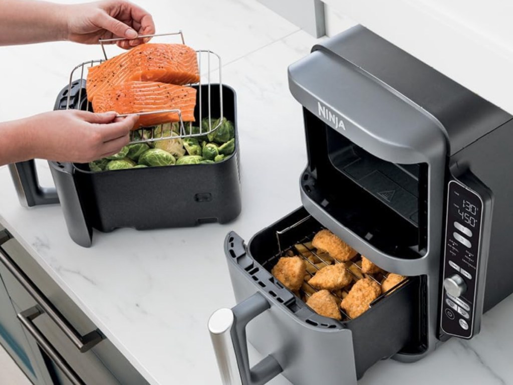 person cooking fish and chicken with the Ninja DoubleStack Air Fryer Bundle