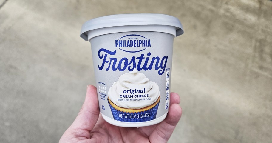 hand holding a tub of Philadelphia Original Cream Cheese Frosting