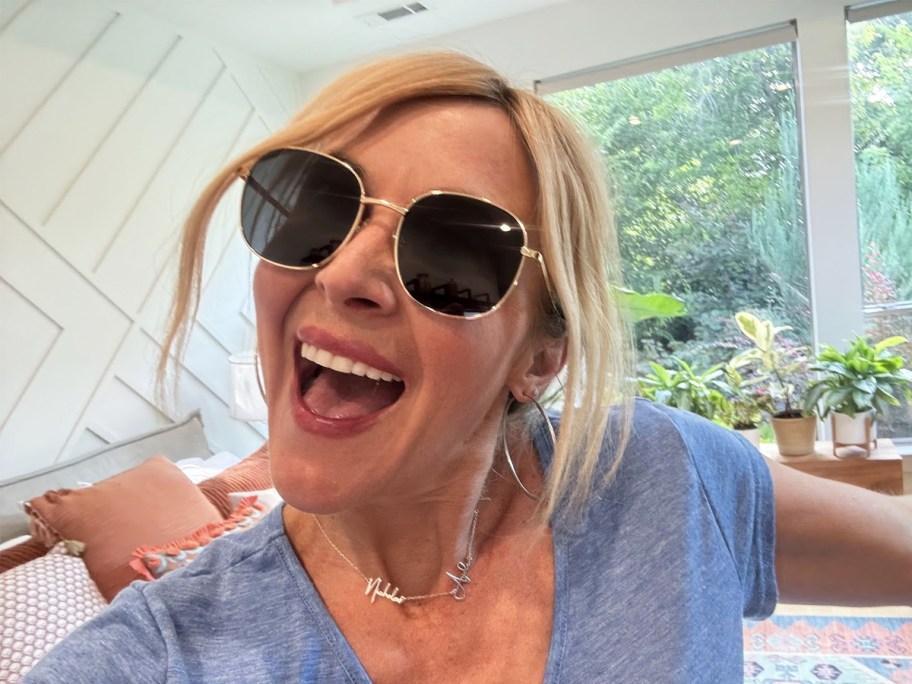 woman in a blue shirt wearing a pair of sunglasses with black lenses