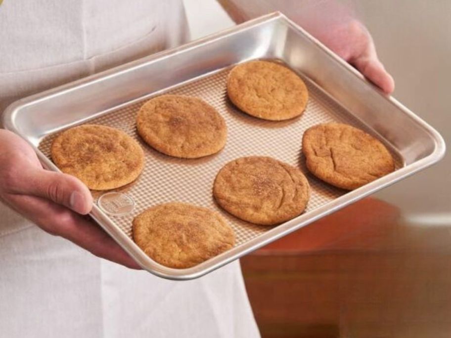 person holding Ultra Cuisine Textured Aluminum 9x13 Baking Sheet with cookies on it