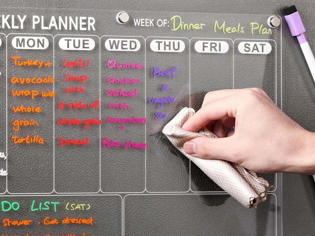 Weekly acrylic planner affixed to gray refrigerator with colorful dry erase marker
