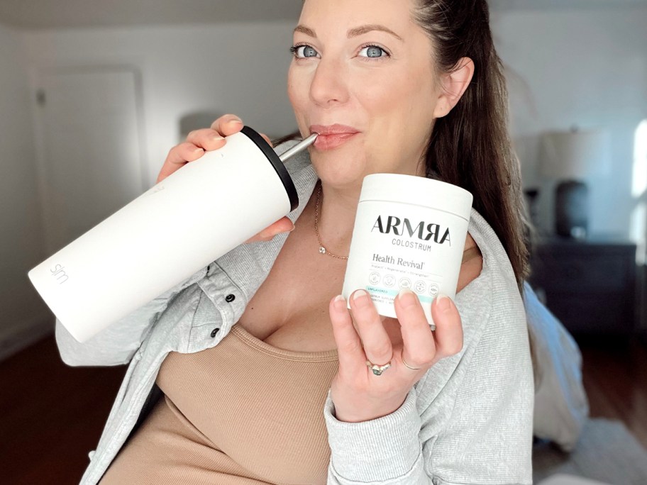 woman holding jar of arma and drinking out of white tumbler