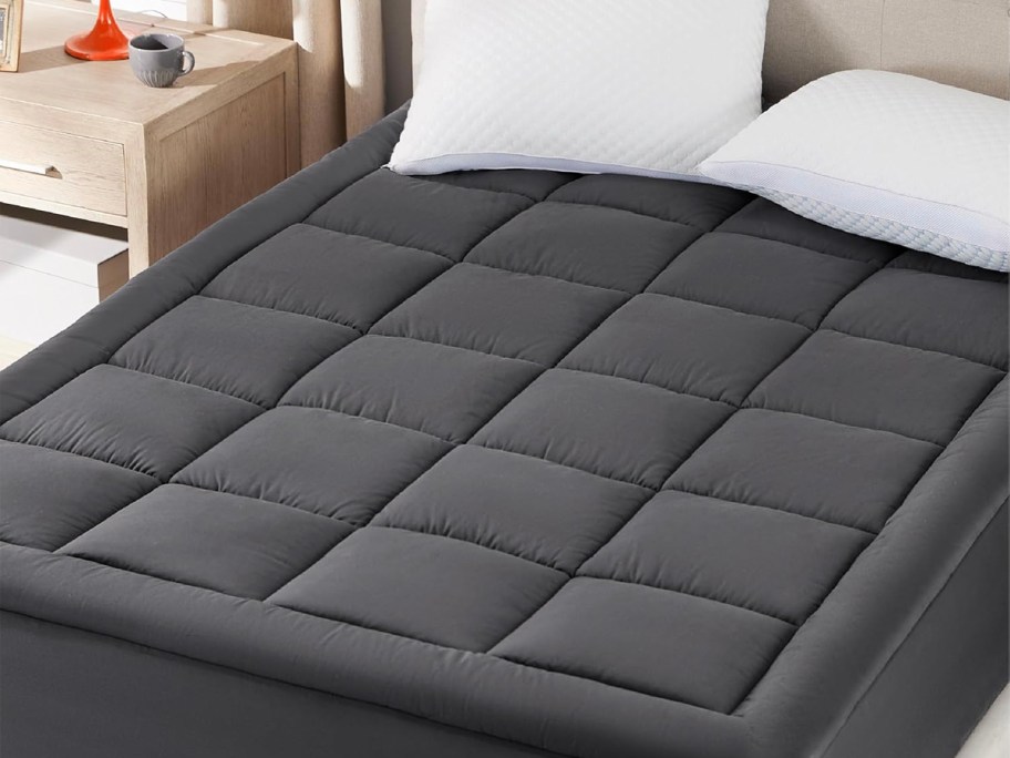 gray mattress pad with white illows on bed