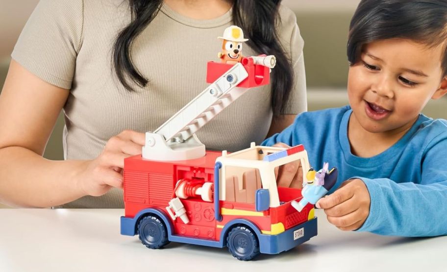 a mom and a toddler playing with the bluey firetruck