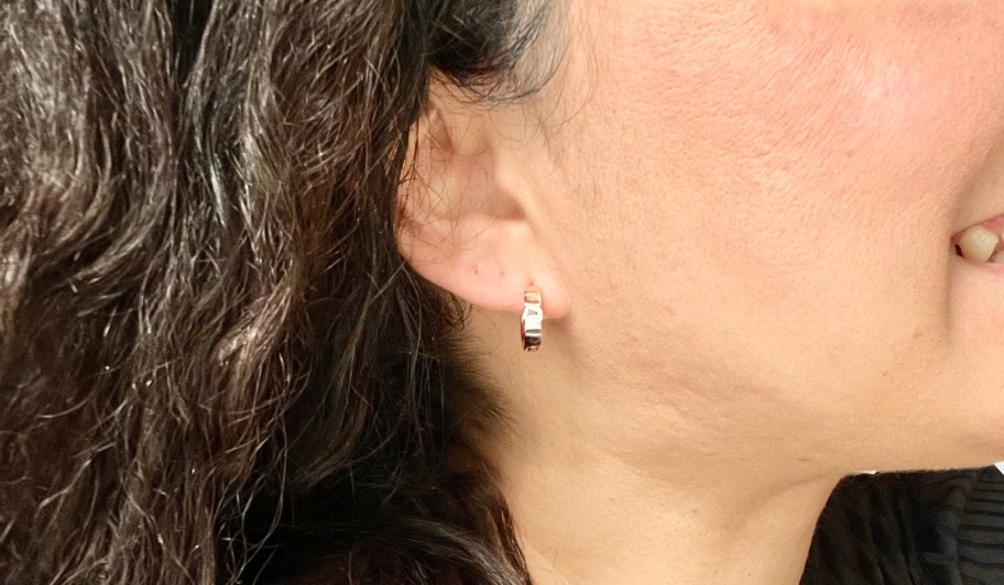 side of ear wearing silver huggie hoop earrings