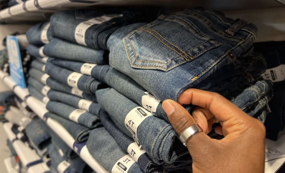 hand grabbing children's place jeans off a store shelf