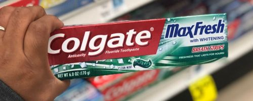 a womans hand holding a tube of colgate max fresh