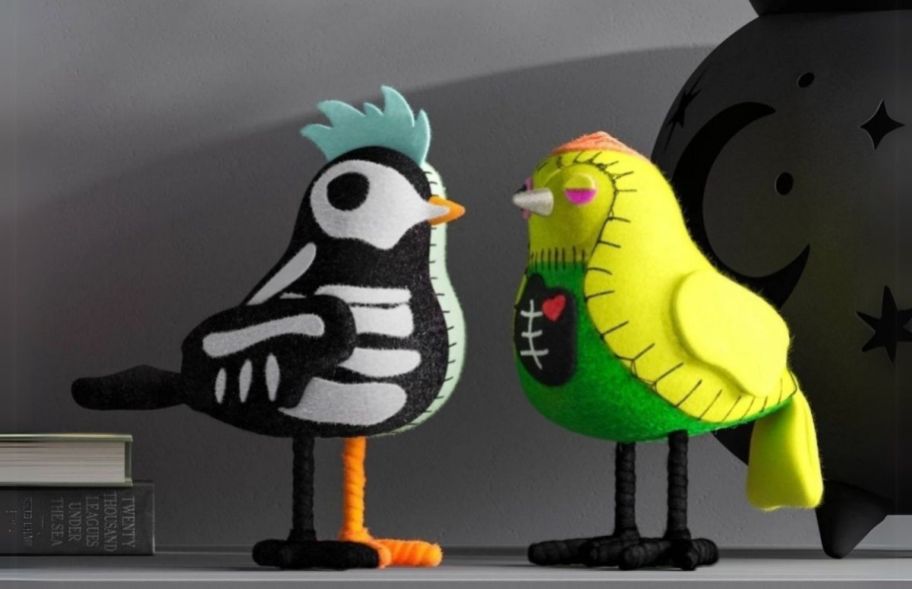 two felt birds dressed in halloween costumes. One as a zombie and the other as a skeleton.