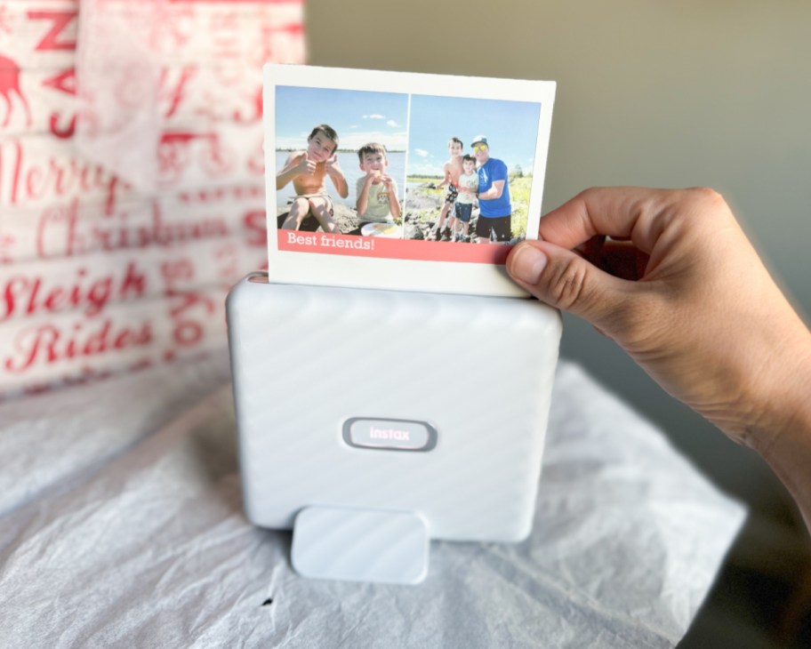 hand removing polaroid from printer