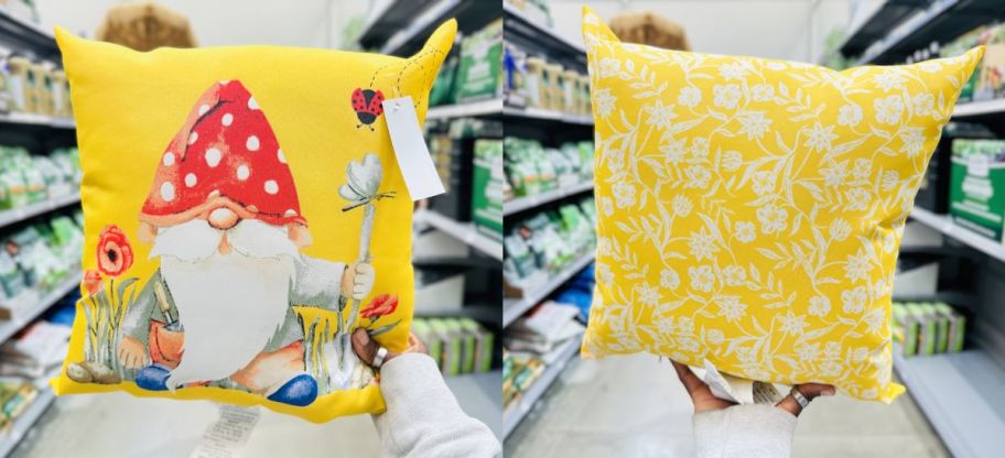 a womans hand holding up a gnome throw pillow on a store aisle