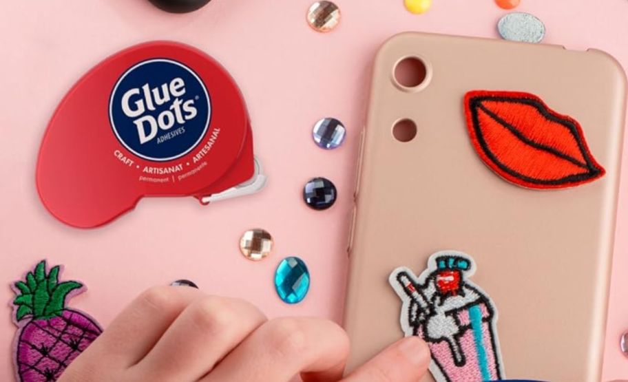 a persons hand applying decorations to a phone case with permanent gluedots