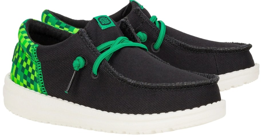 kids HEYDUDE shoes in black with green grid on the heels and green laces