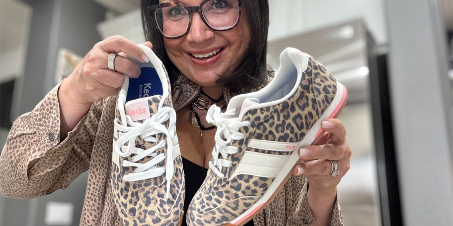 woman holding pair of keds shoes 