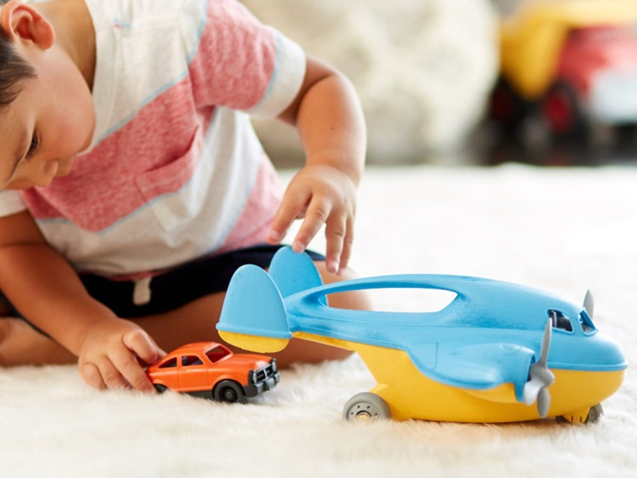 kid playing with Green Toys Cargo Plane on the rug