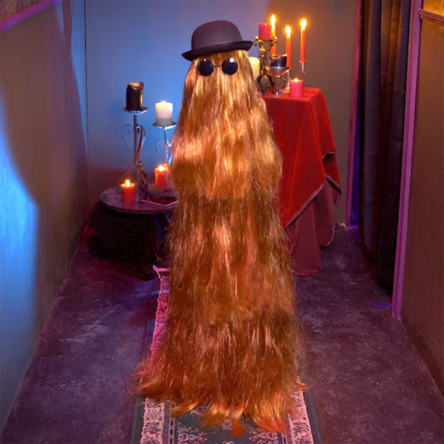 an Adams Family Cousin Itt (character with really long hair from his head to his feet all around his body wearing a hat and sunglasses) animatronic