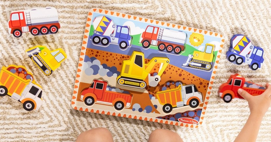 a kid's wooden puzzle with large pieces that look like construction vehicles on the floor