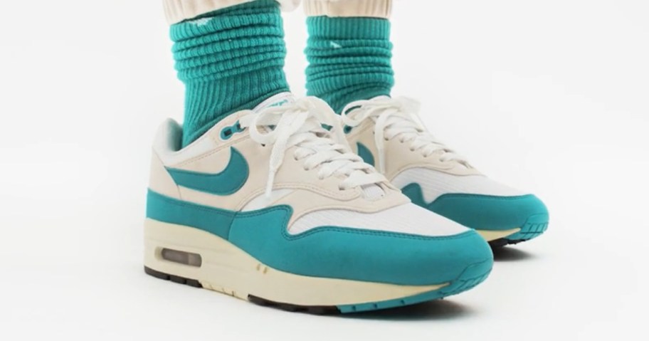 women's feet wearing teal green Nike socks with Nike Air Max shoes in teal green, off white, and white