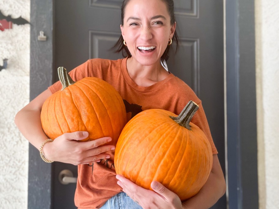 woman holding 2 pumpkins