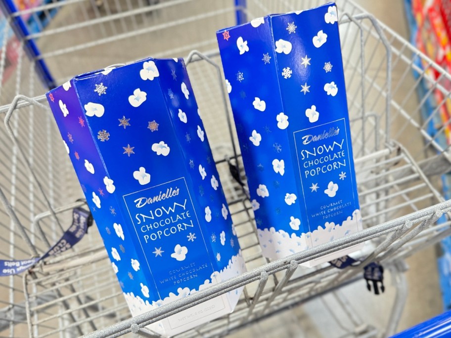 2 blue and white bags of Snowy White Chocolate Popcorn in a Sam's Club cart