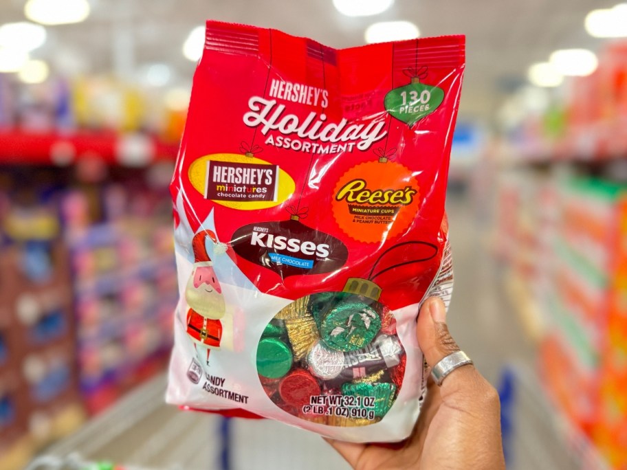 hand holding a large bag of HERSHEY'S Holiday Assortment, Chocolate Candy