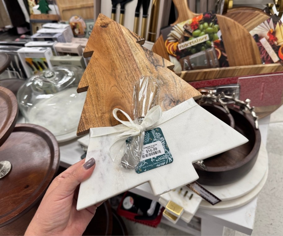 womans hand holding a wood and marlble tree shaped cheese board