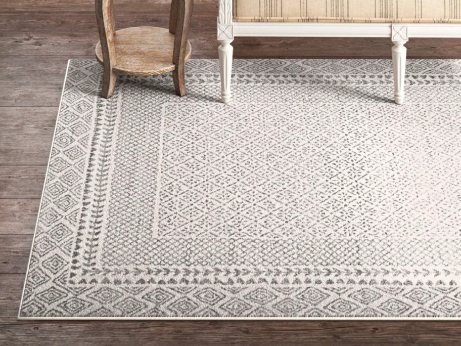 a large grey and white print area rug in a living room