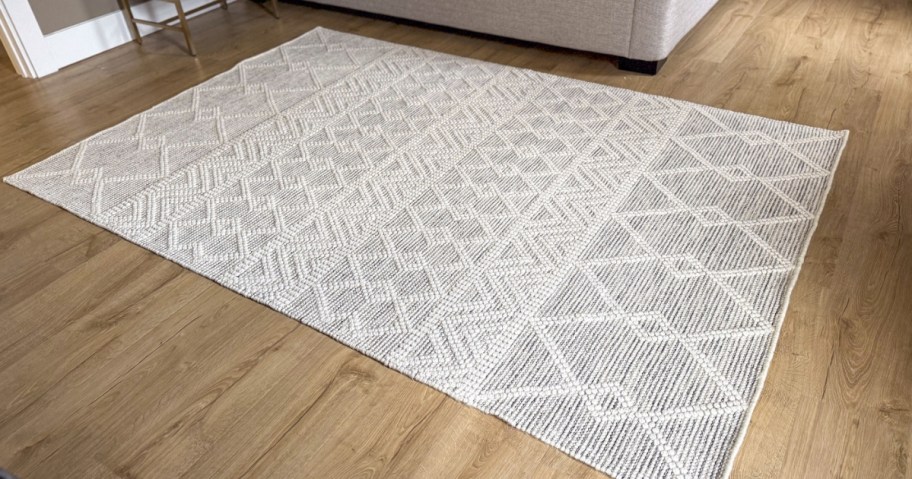 a large grey and cream geometric print area rug in a bedroom