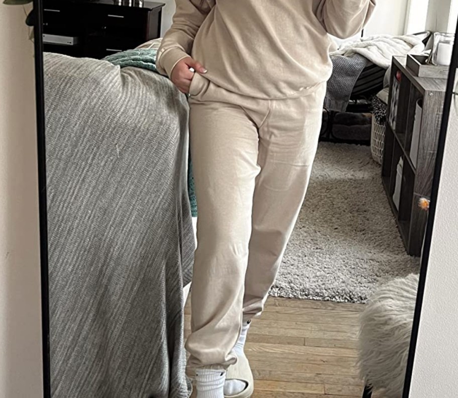 a woman in a pair of sweatpants taking a selfie
